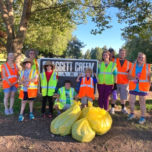 group of people in front of a park sign with bags of trash